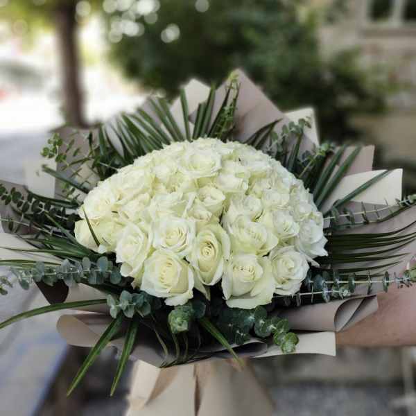 Bouquet of white roses with greenery and beige wrapping