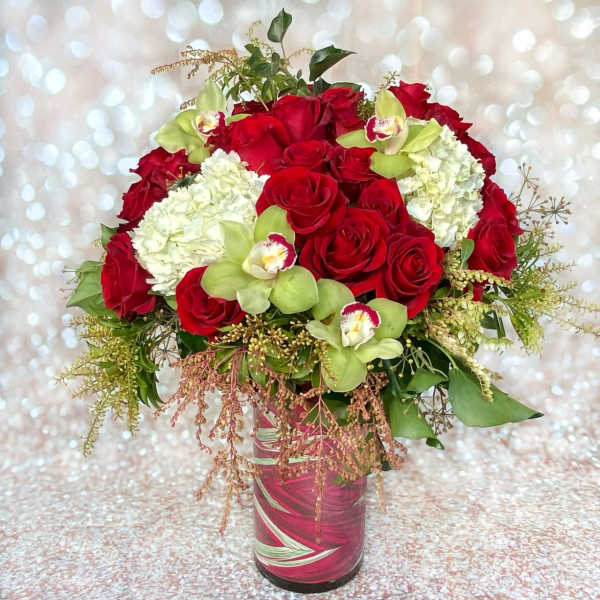 Red roses and white hydrangeas with green orchids in a glass vase