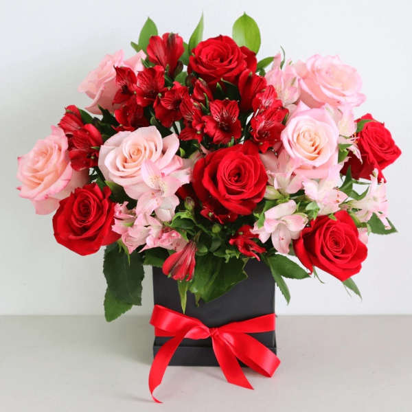 Bouquet of red and pink roses with red alstroemeria in a black box