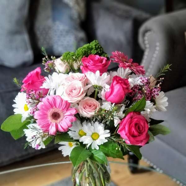 Pink roses and daisies arranged in a clear glass vase