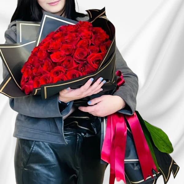 Large bouquet of red roses wrapped in black paper with pink ribbon