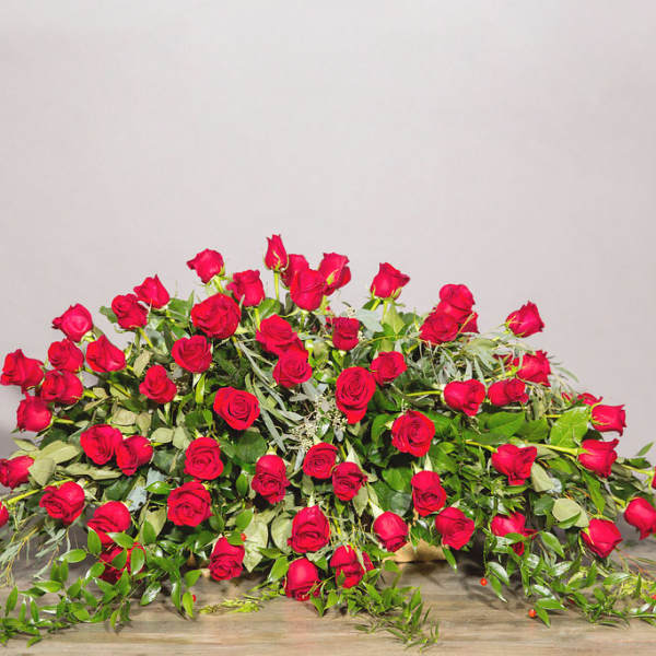 Large arrangement of red roses with trailing greenery on a table