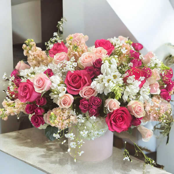 Pink and white rose arrangement in a pale vase