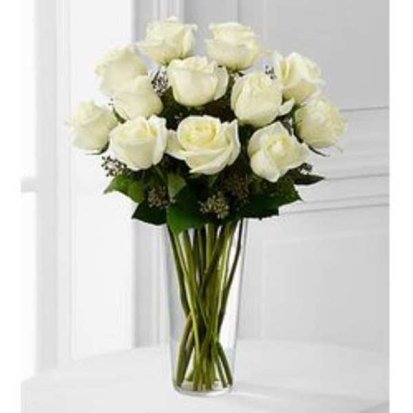 Tall clear glass vase with a dozen white roses arranged in a rounded bouquet
