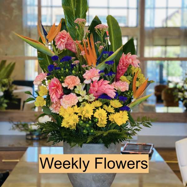 Tall mixed flower arrangement in a gray vase with bright tropical blooms