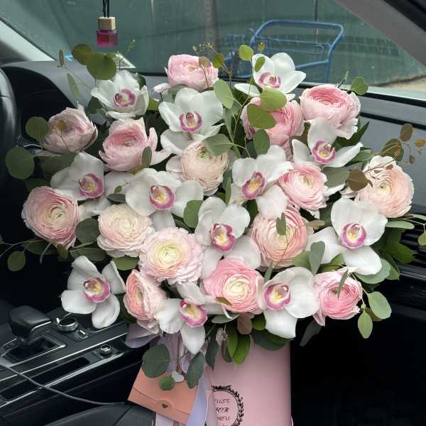 Pink ranunculus and white orchids in a pink hatbox