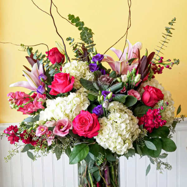 Large mixed bouquet of pink, white, and purple flowers in a glass vase