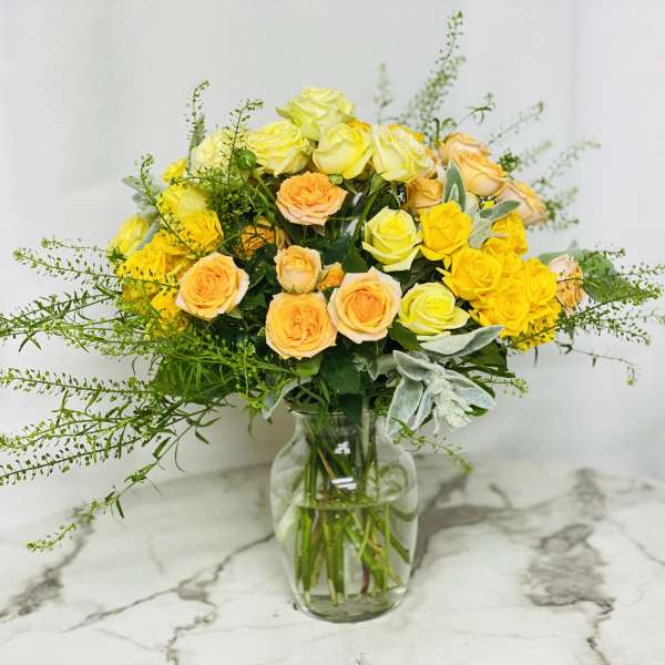Yellow and peach roses in a clear glass vase