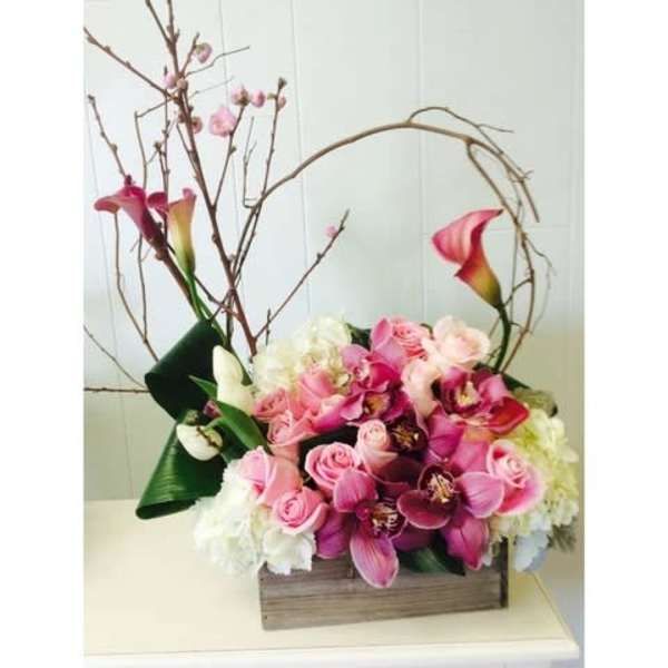 Pink and white floral arrangement with calla lilies and orchids in a wooden box