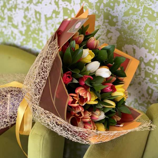 Bouquet of multicolored tulips wrapped in decorative paper and mesh