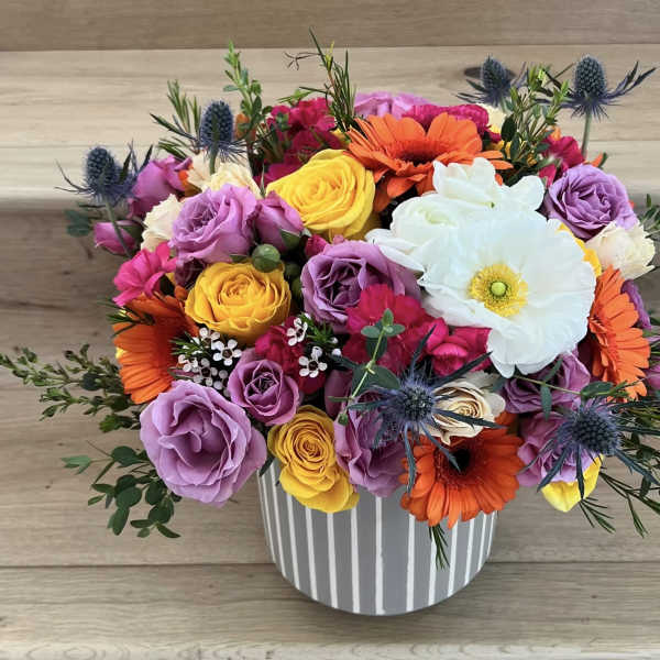 Colorful bouquet of roses, gerbera daisies, and a white anemone in a striped vase