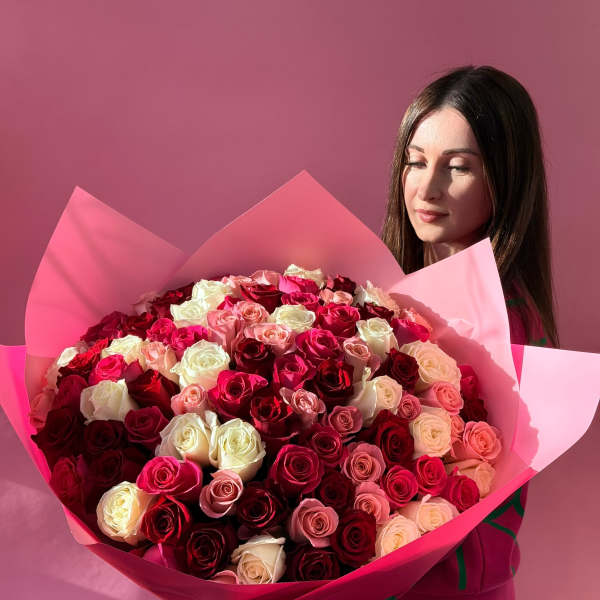 Large bouquet of pink, red, and white roses wrapped in pink paper