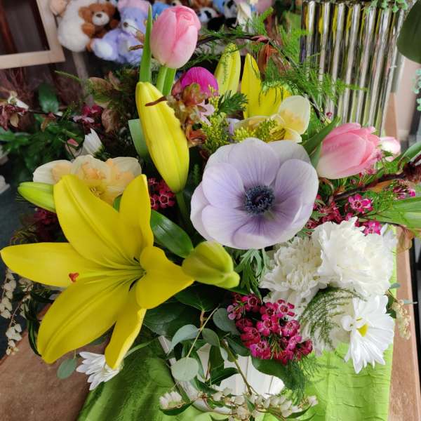 Mixed bouquet with yellow lilies, pink tulips, and a pale purple anemone