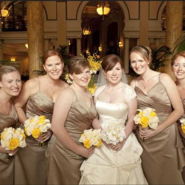 Bride and bridesmaids holding white and yellow bouquets indoors