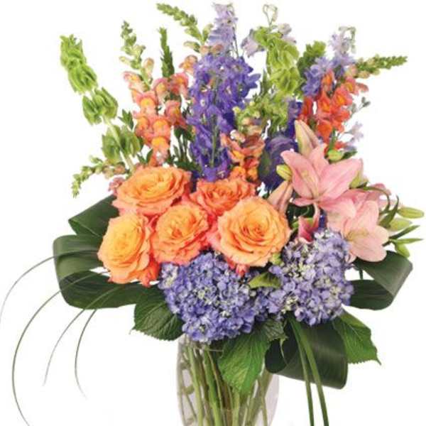 Mixed bouquet of orange roses, purple flowers, and pink lilies in a glass vase
