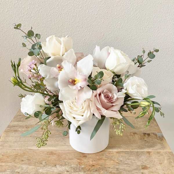 White and blush roses with orchids in a white vase