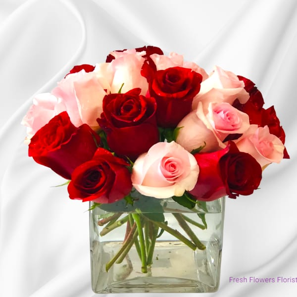 Red and pink roses arranged in a clear square vase