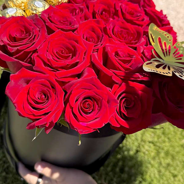 Red roses in a black hat box with gold-wrapped chocolates
