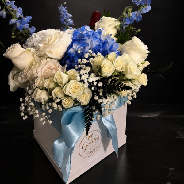 Blue and white floral arrangement in a white gift box with a ribbon