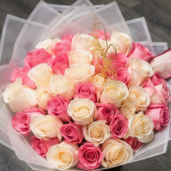 Bouquet of pink and cream roses wrapped in translucent paper