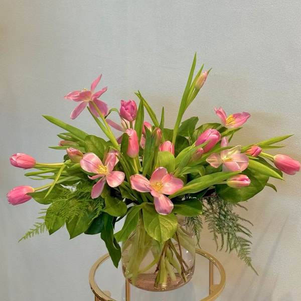 Pink tulips and open pink flowers in a clear glass vase