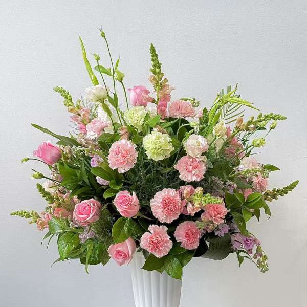 Pink roses and carnations arranged in a white vase