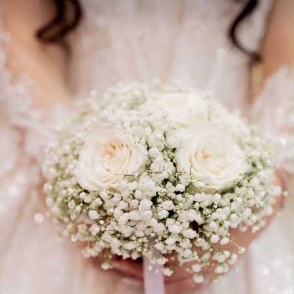 Bride holding a white rose bouquet with baby's breath