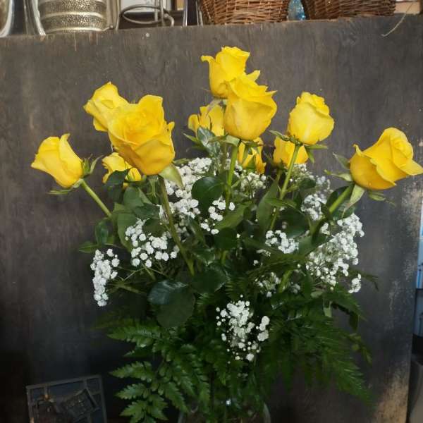 Yellow roses in a clear glass vase with white filler flowers