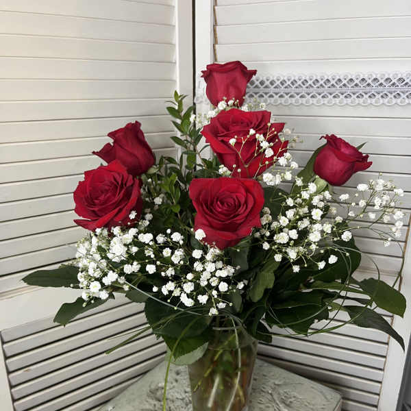 Red roses with baby's breath in a clear glass vase
