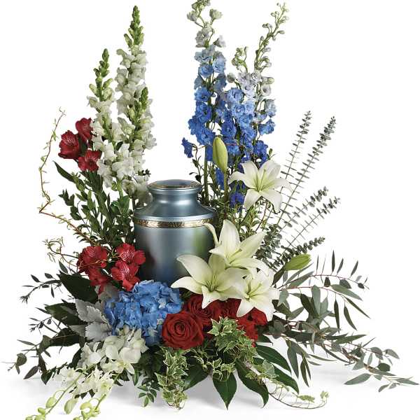 Sympathy arrangement with red roses, white lilies, blue flowers, and a blue urn