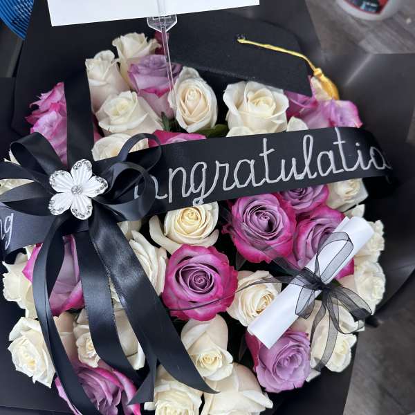 Bouquet of pink, lavender, and white roses with a congratulatory ribbon