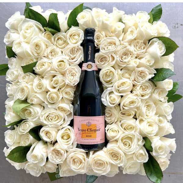 White rose arrangement surrounding a champagne bottle