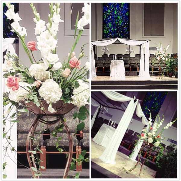 White floral arrangement on a tall stand with pink roses