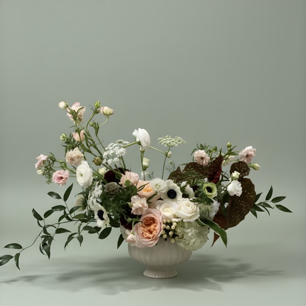 Mixed pastel floral arrangement in a white pedestal vase