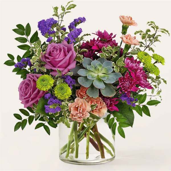 Mixed bouquet in a clear glass vase with purple roses and succulents