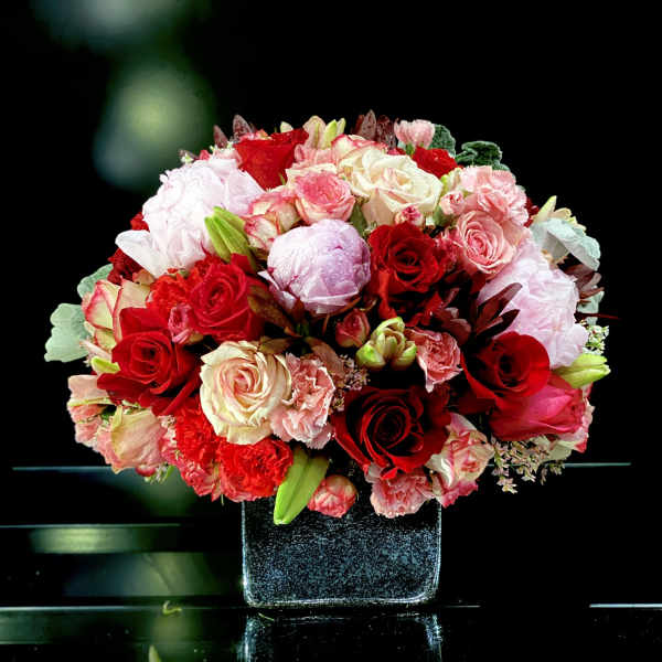 Bouquet of red, pink, and white roses in a square vase
