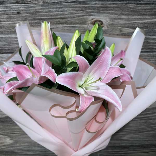 Bouquet of pink lilies wrapped in pale pink paper