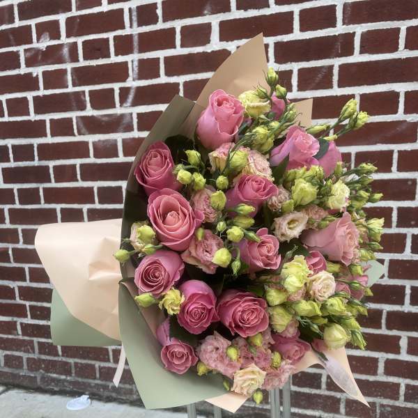 Bouquet of pink roses and pale lisianthus wrapped in pastel paper
