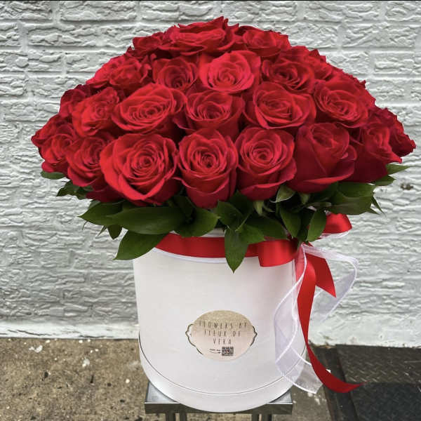 Red roses arranged in a white hat box with a red ribbon