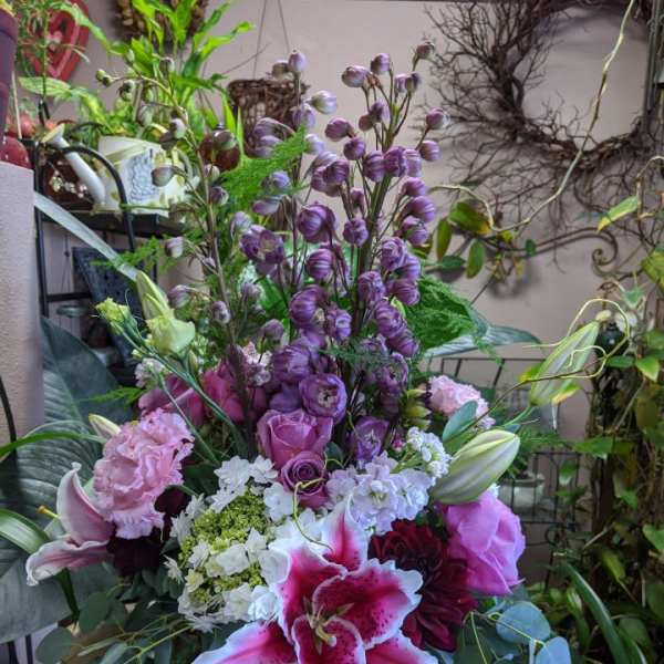 Mixed bouquet with pink lilies, roses, and purple blooms in a glass vase