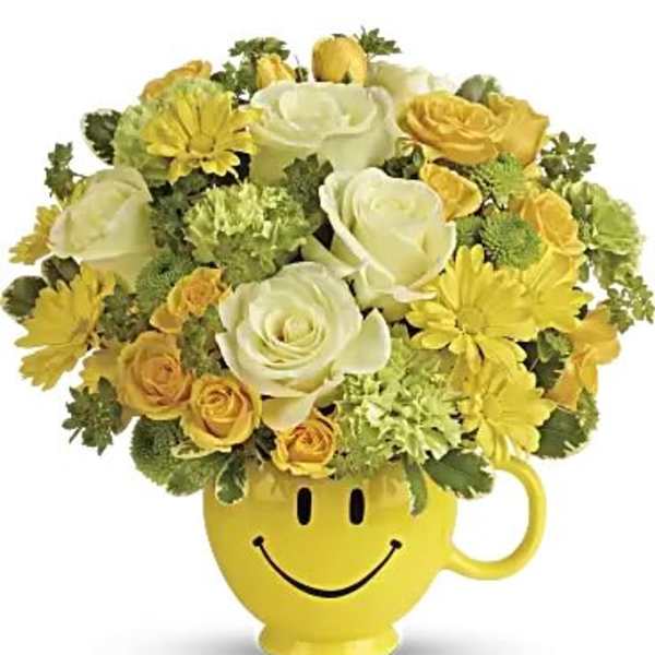 Yellow and white flower arrangement in a smiley-face mug