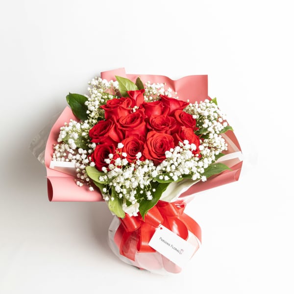 Bouquet of red roses with white baby's breath in pink wrapping