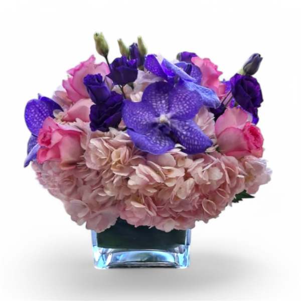 Pink and purple floral arrangement in a clear square vase