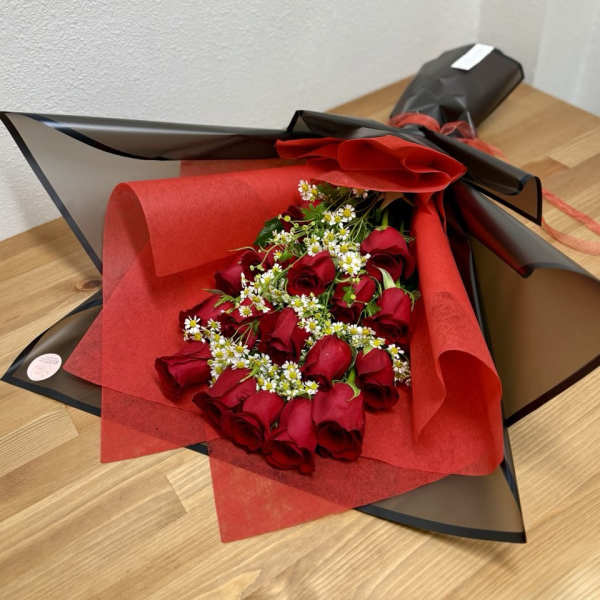 Bouquet of red roses with small white filler flowers in black and red wrap