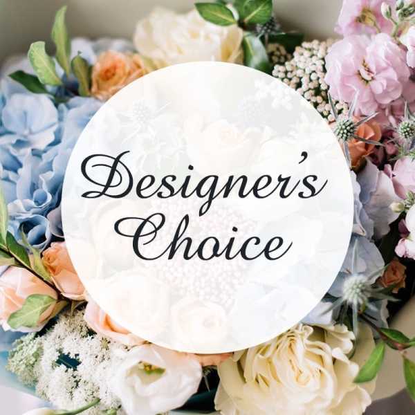 Assorted pastel flowers arranged around a "Designer's Choice" sign