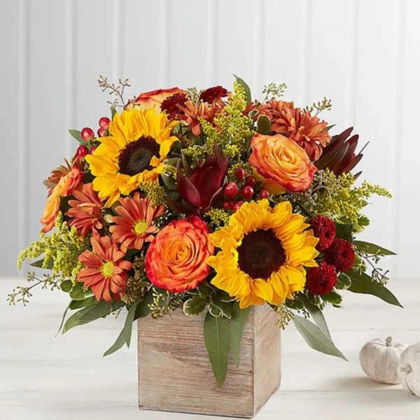Autumn bouquet with sunflowers, orange roses, and mums in a wooden box