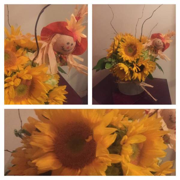Sunflower arrangement with a small scarecrow decoration in a container