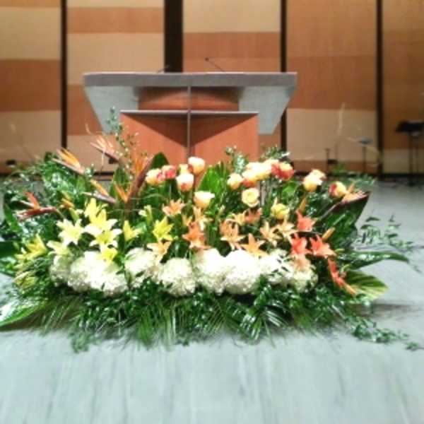 Large low altar arrangement with white hydrangeas, yellow lilies, peach roses and lush greenery