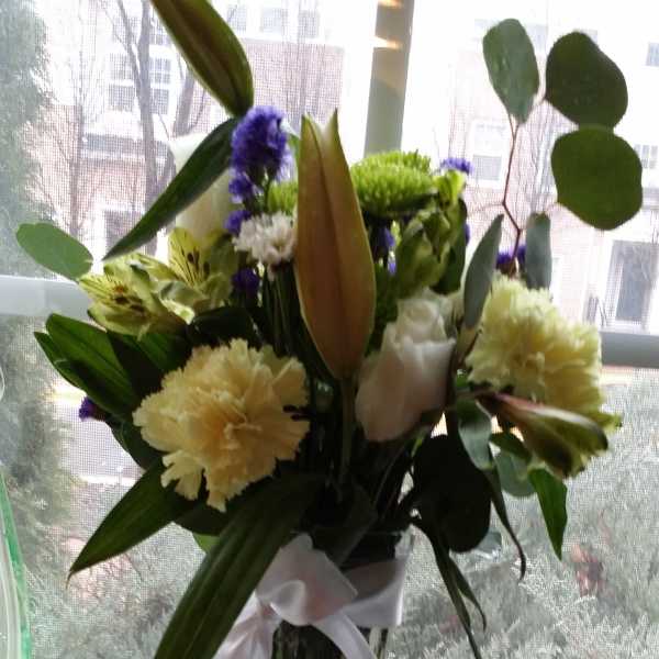 Mixed bouquet in a tall glass vase with white ribbon