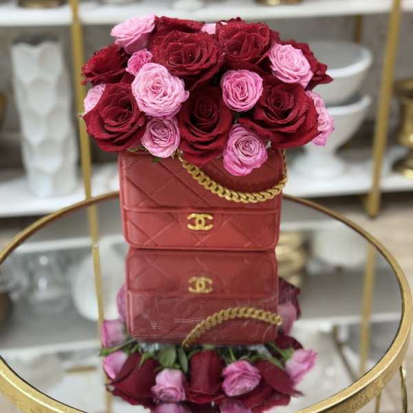 Red and pink roses arranged in a red handbag-shaped box